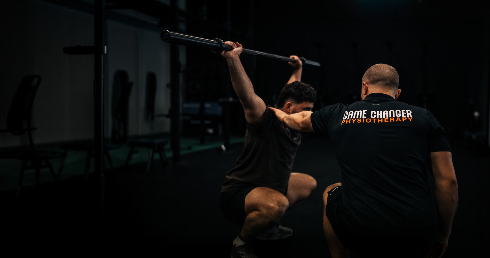 Game Changer physiotherapist coaching an athlete through an overhead barbell squat inside New Movement Gym, Osborne Park
